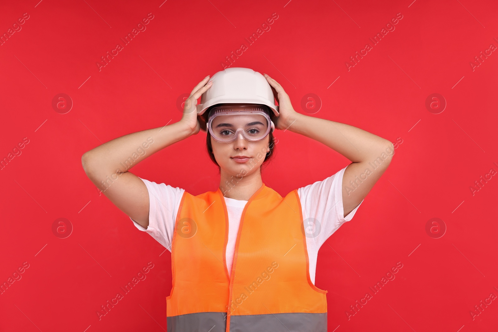 Photo of Girl with safety equipment on red background. Work for teenagers