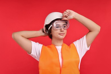 Photo of Girl with safety equipment on red background. Work for teenagers