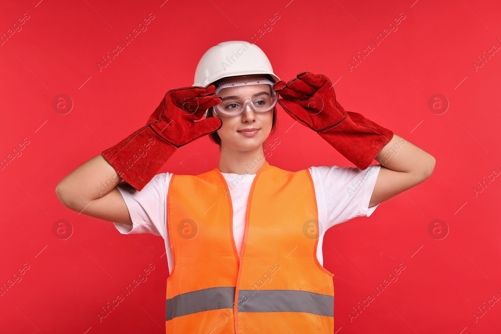 Photo of Girl with safety equipment on red background. Work for teenagers