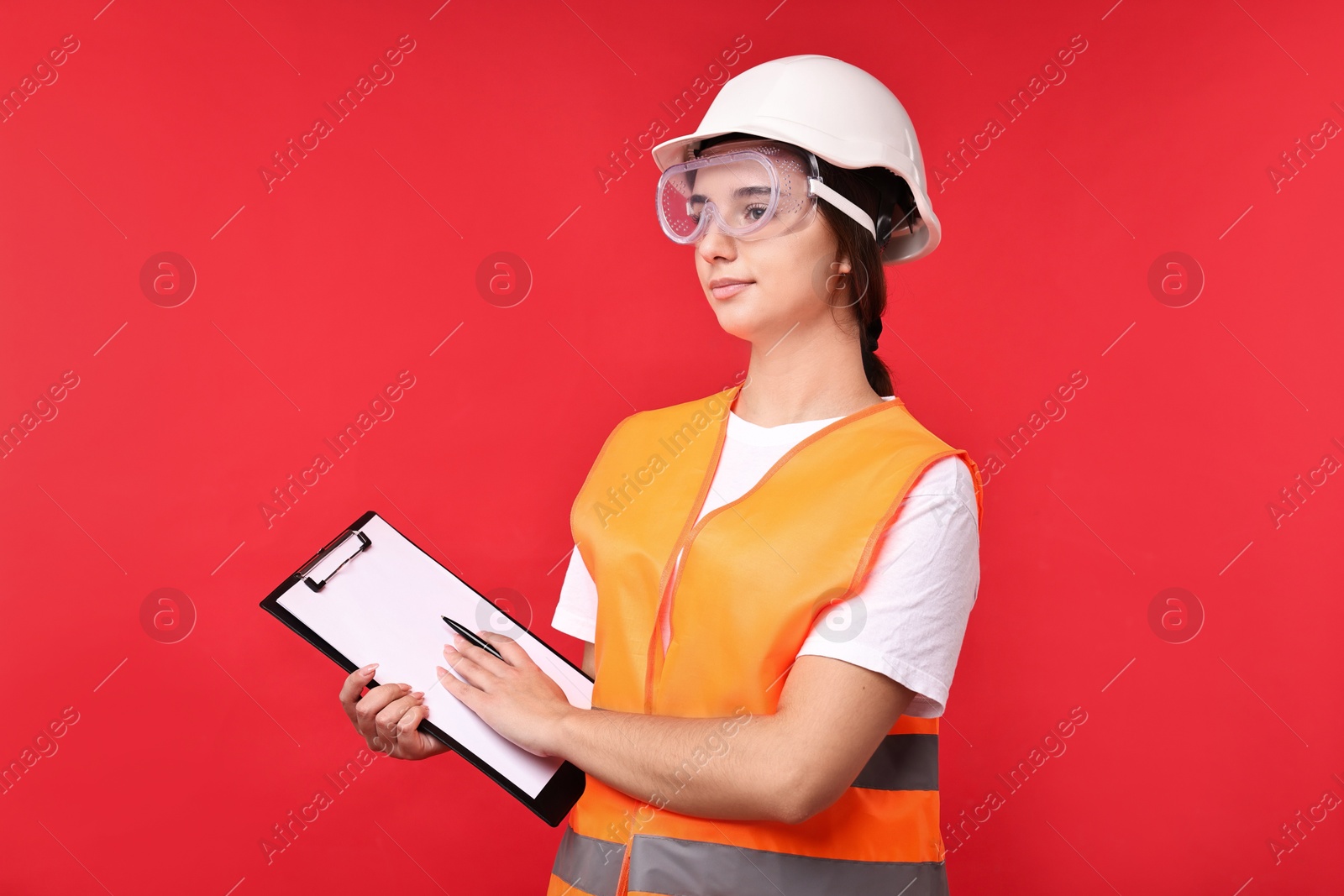 Photo of Girl with safety equipment and clipboard on red background. Work for teenagers