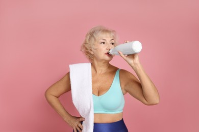 Photo of Senior woman with towel and water on pink background