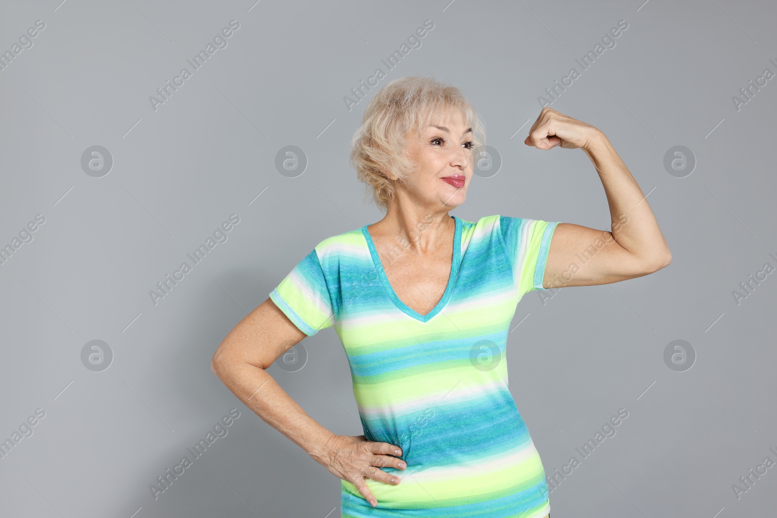 Photo of Senior woman exercising on light grey background