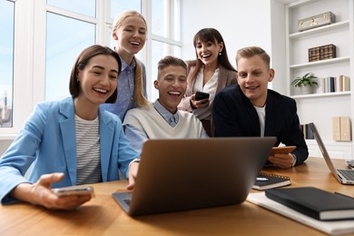 Photo of Group of people using different gadgets at wooden table in office. Modern technology