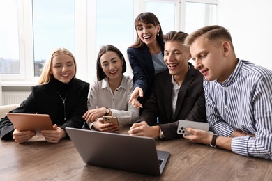 Group of people using different gadgets at wooden table in office. Modern technology