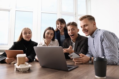 Photo of Group of people using different gadgets at wooden table in office. Modern technology