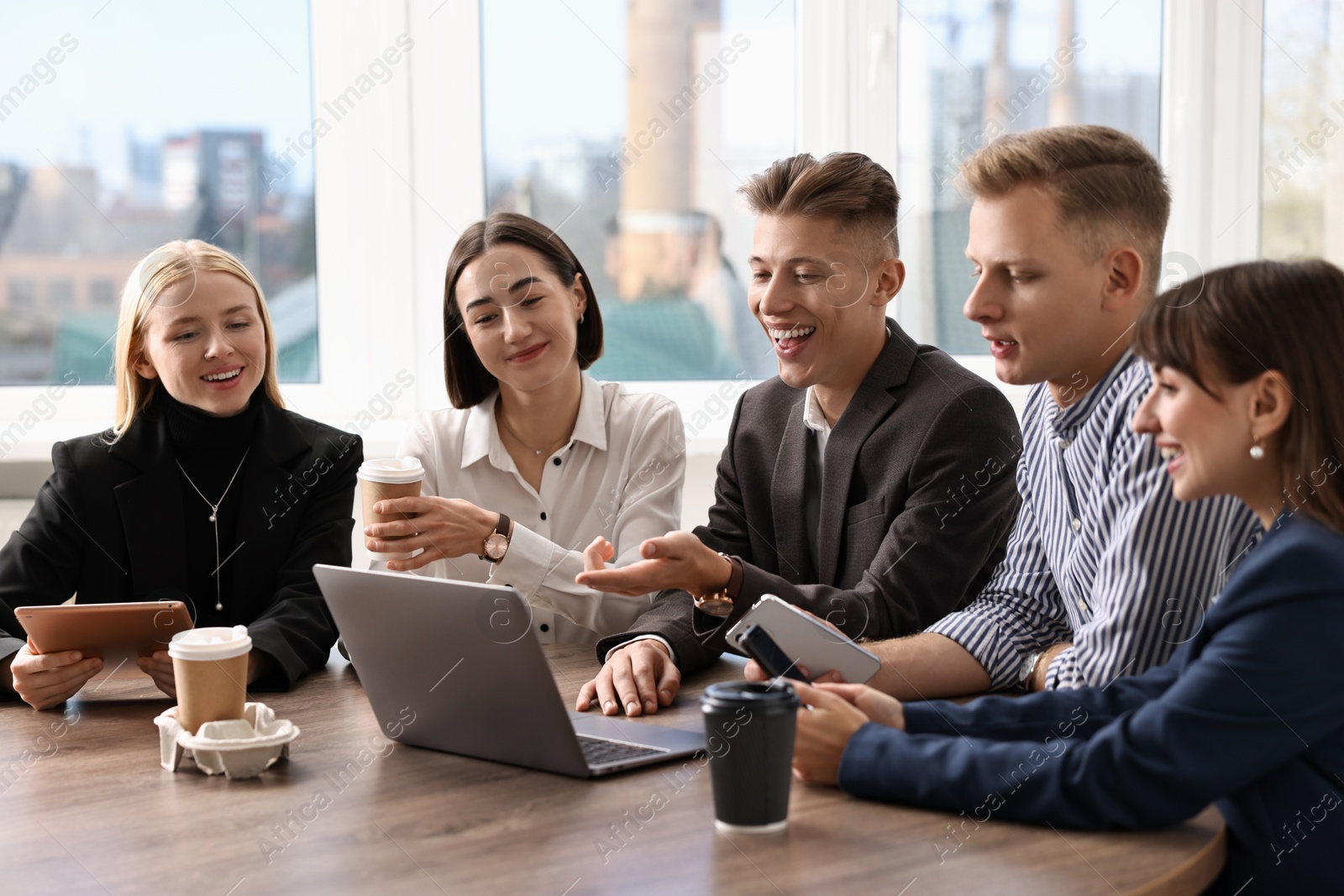 Photo of Group of people using different gadgets at wooden table in office. Modern technology