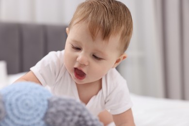 Photo of Cute little baby with toy on bed at home