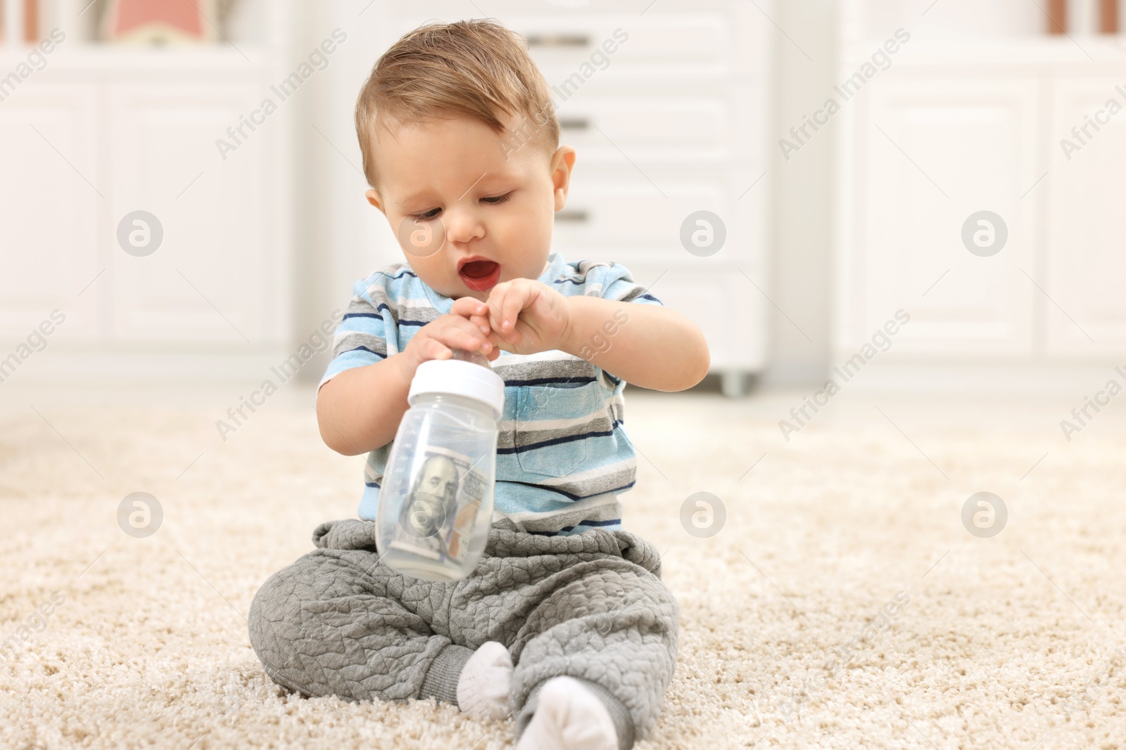 Photo of Little baby with money in bottle at home