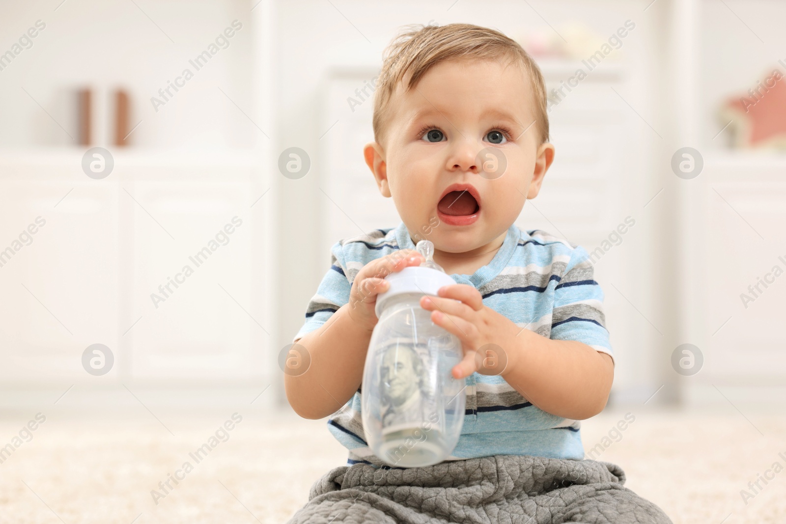 Photo of Little baby with money in bottle at home. Space for text