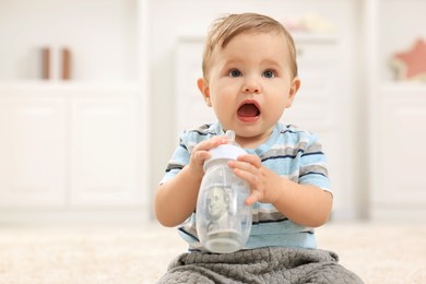 Photo of Little baby with money in bottle at home. Space for text