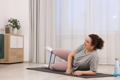 Photo of Woman training with resistance band at home