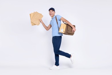 Photo of Happy postman with bag and envelopes on white background