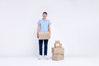 Photo of Happy postman with stack of parcels on white background