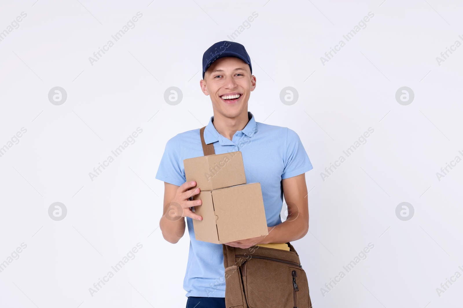 Photo of Happy postman with bag and parcels on white background