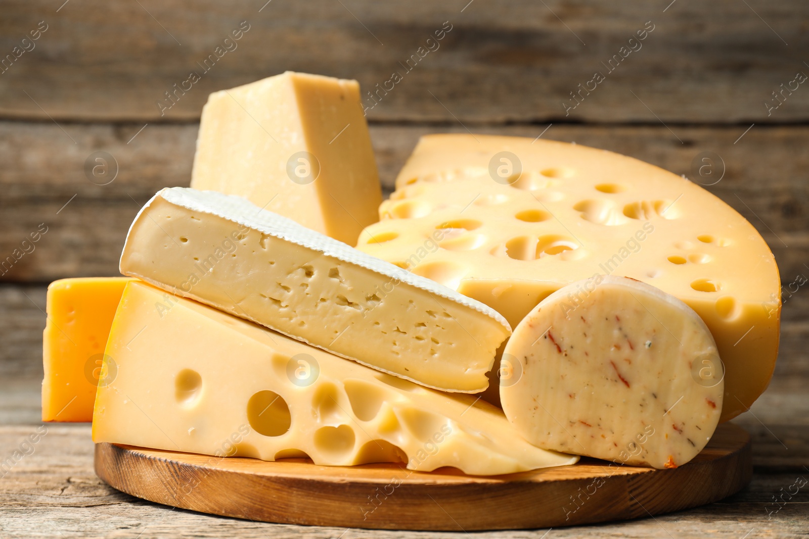 Photo of Different types of cheese on wooden table, closeup