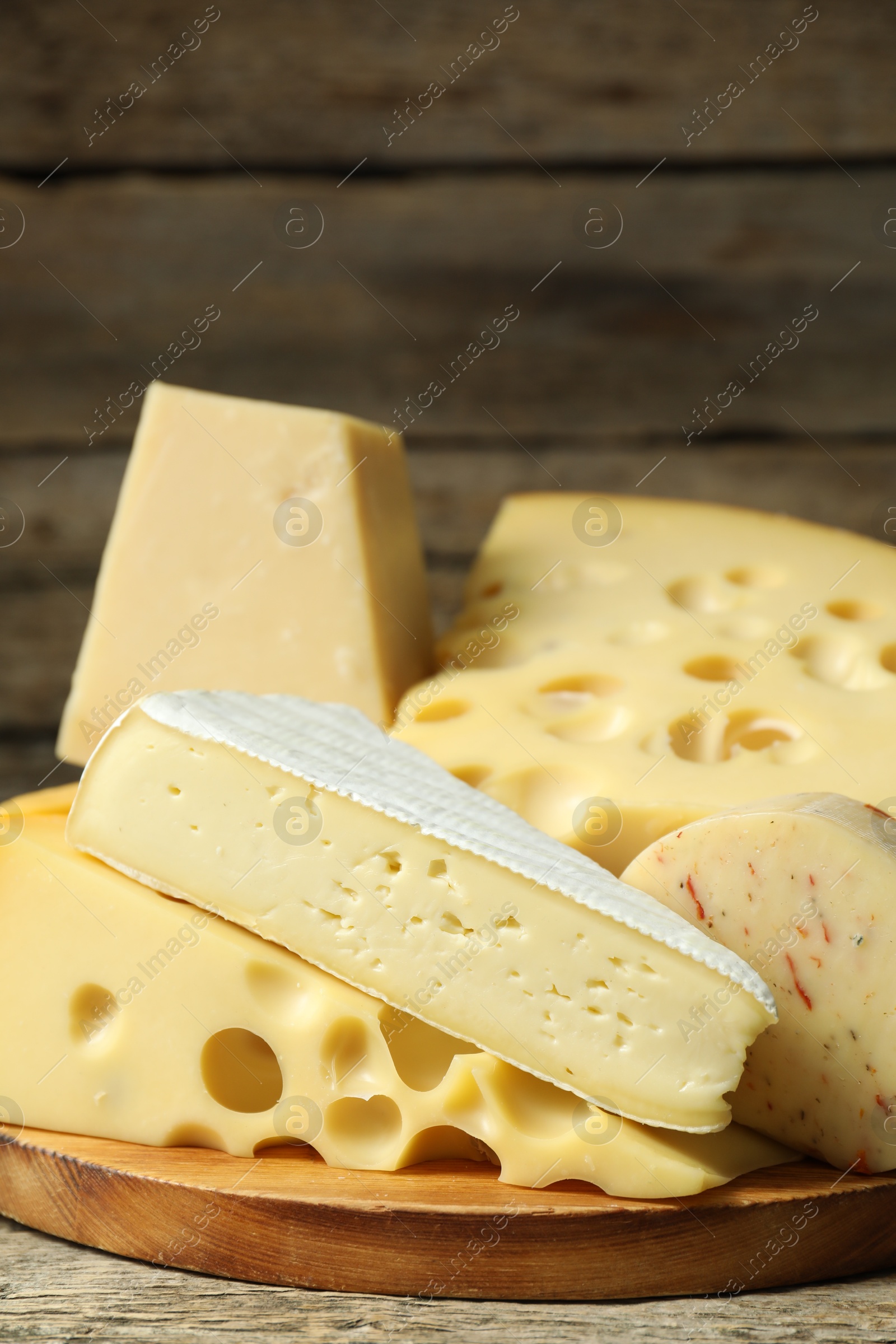 Photo of Different types of cheese on wooden table, closeup