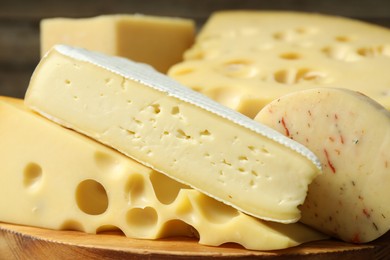 Photo of Different types of cheese on wooden board, closeup