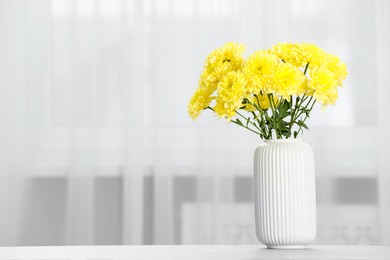 Photo of Beautiful yellow flowers in vase on table at home, space for text