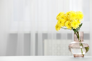 Photo of Beautiful yellow flowers in vase on table at home, space for text