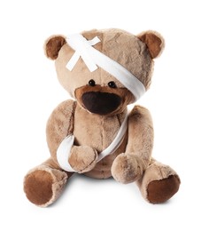 Photo of Teddy bear with bandages and adhesive medical plasters isolated on white