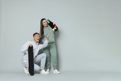 Photo of Happy friends with skateboards on light grey background. Space for text