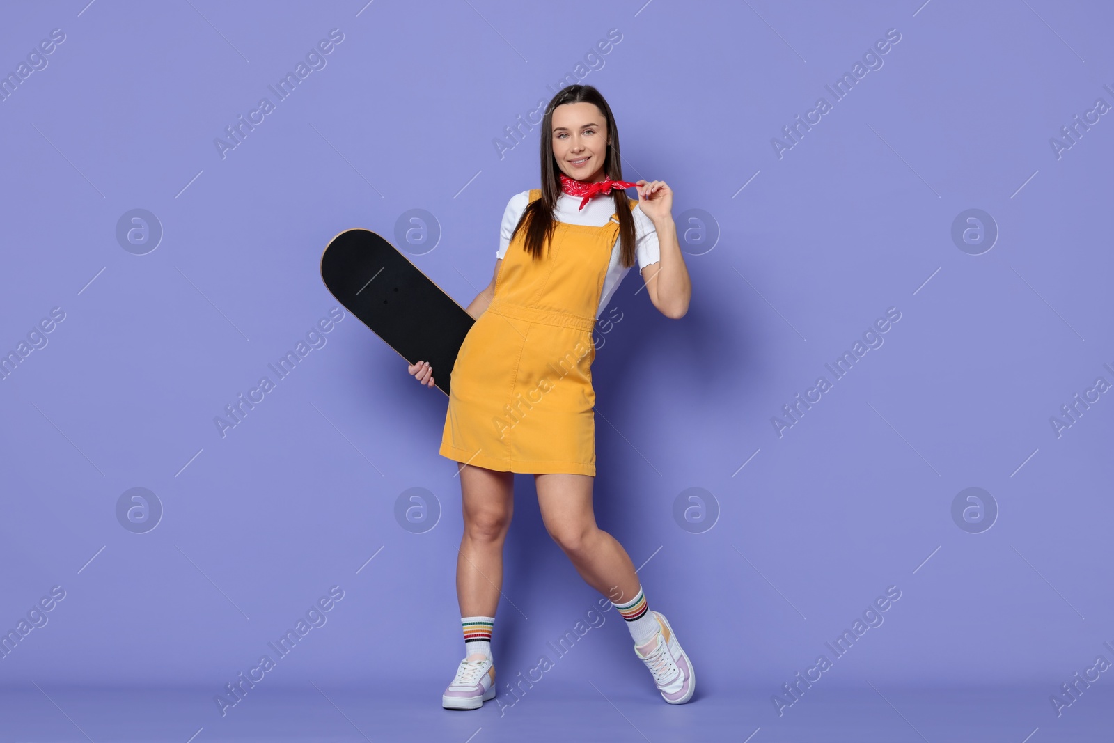 Photo of Smiling woman with skateboard on violet background