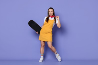 Photo of Smiling woman with skateboard on violet background