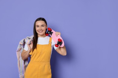 Photo of Smiling woman with penny board on violet background. Space for text