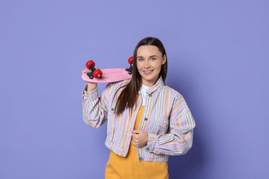 Photo of Smiling woman with penny board on violet background