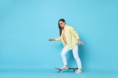 Photo of Smiling woman with skateboard on light blue background. Space for text