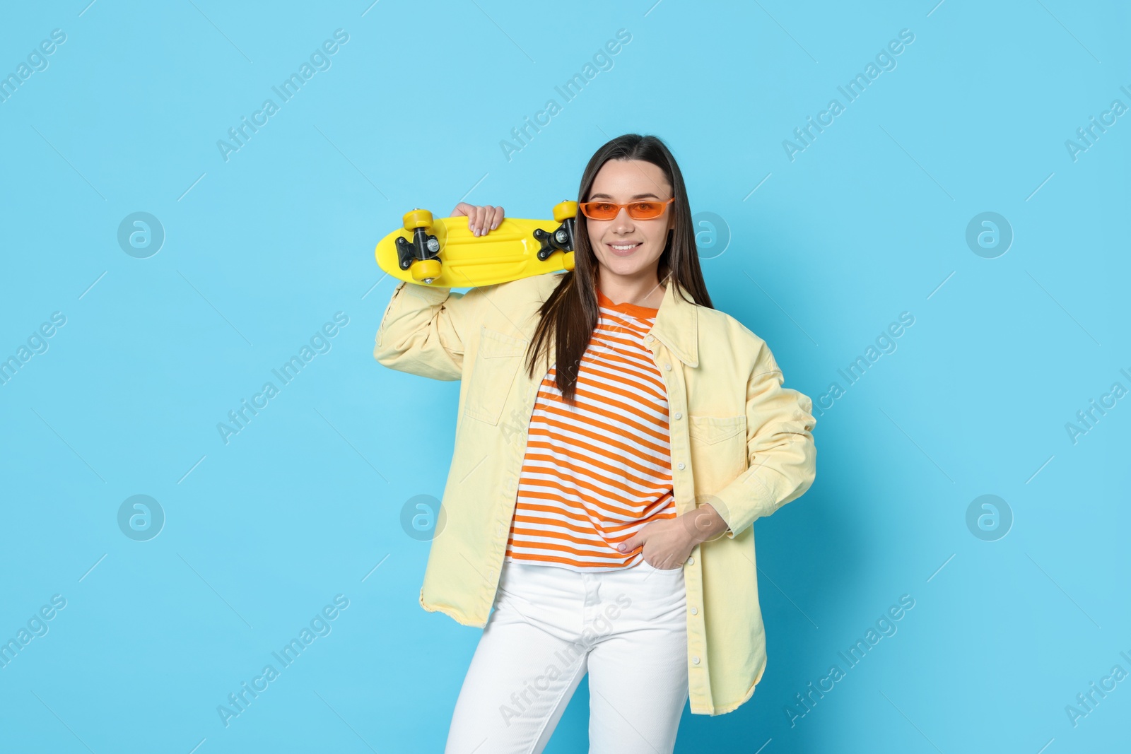 Photo of Smiling woman with penny board on light blue background