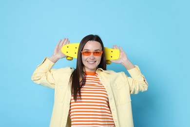 Photo of Smiling woman with penny board on light blue background