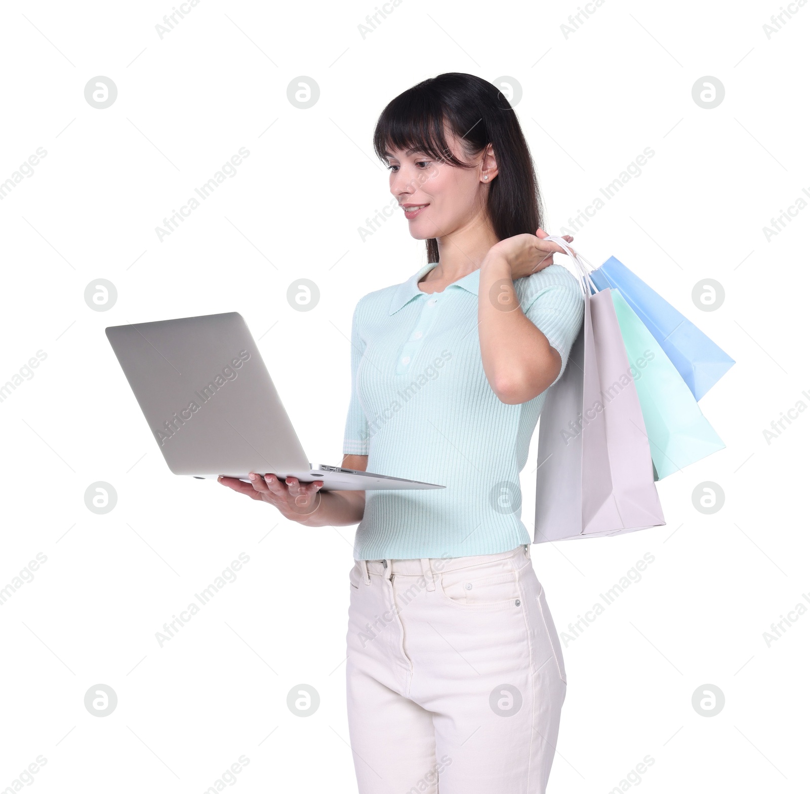 Photo of Internet shopping. Happy woman with laptop and colorful bags on white background