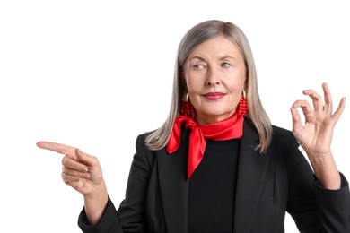 Photo of Senior woman showing okay gesture while pointing at something on white background