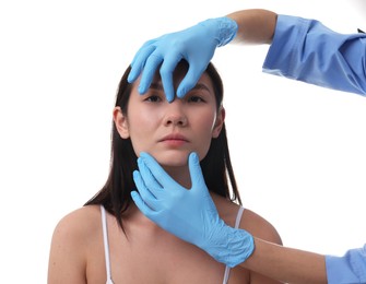 Photo of Doctor checking patient's nose before plastic surgery operation on white background, closeup