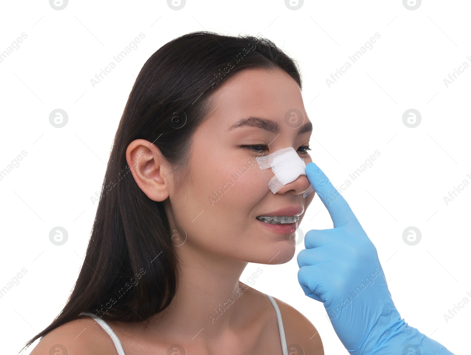 Photo of Doctor checking patient's nose after plastic surgery operation on white background, closeup