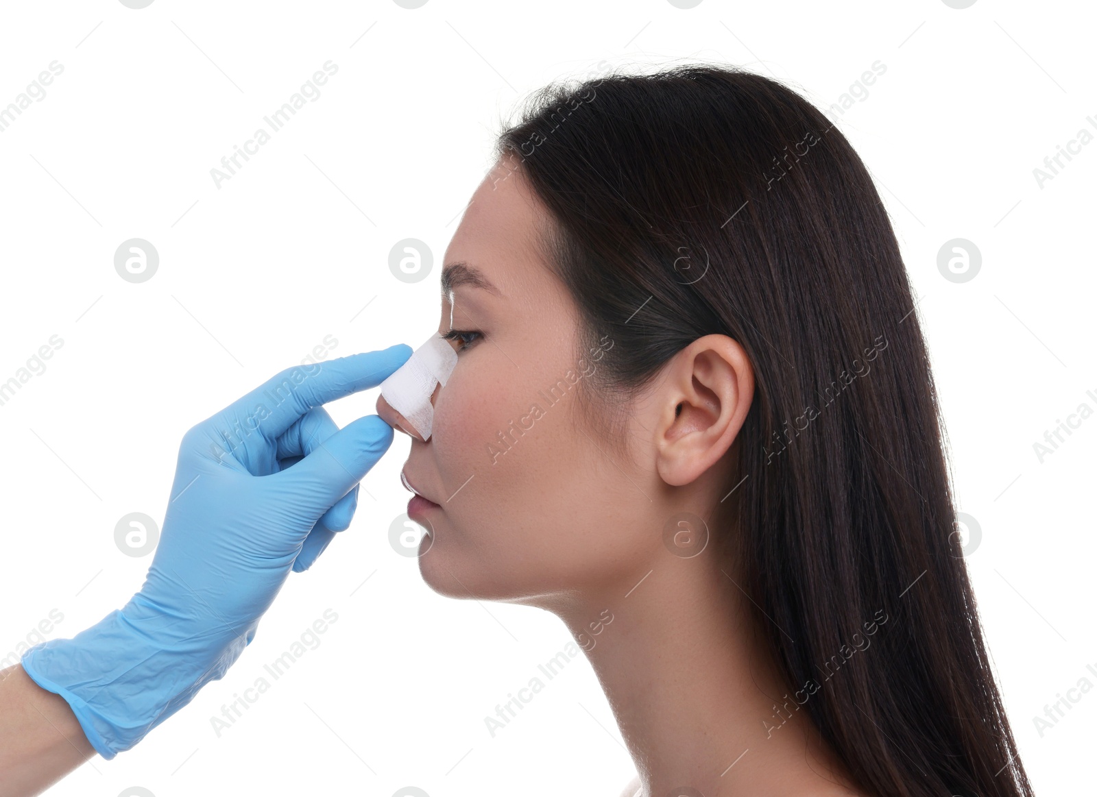 Photo of Doctor checking patient's nose after plastic surgery operation on white background, closeup