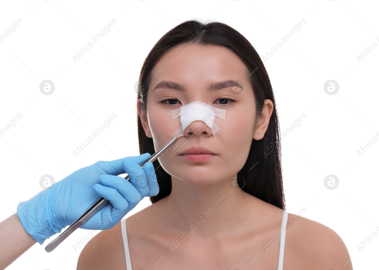 Photo of Doctor removing medical bandage from patient's nose after plastic surgery operation on white background, closeup