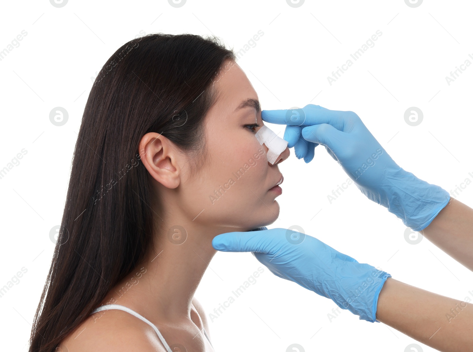 Photo of Doctor checking patient's nose after plastic surgery operation on white background, closeup