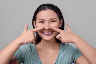 Photo of Woman touching her nose on light grey background