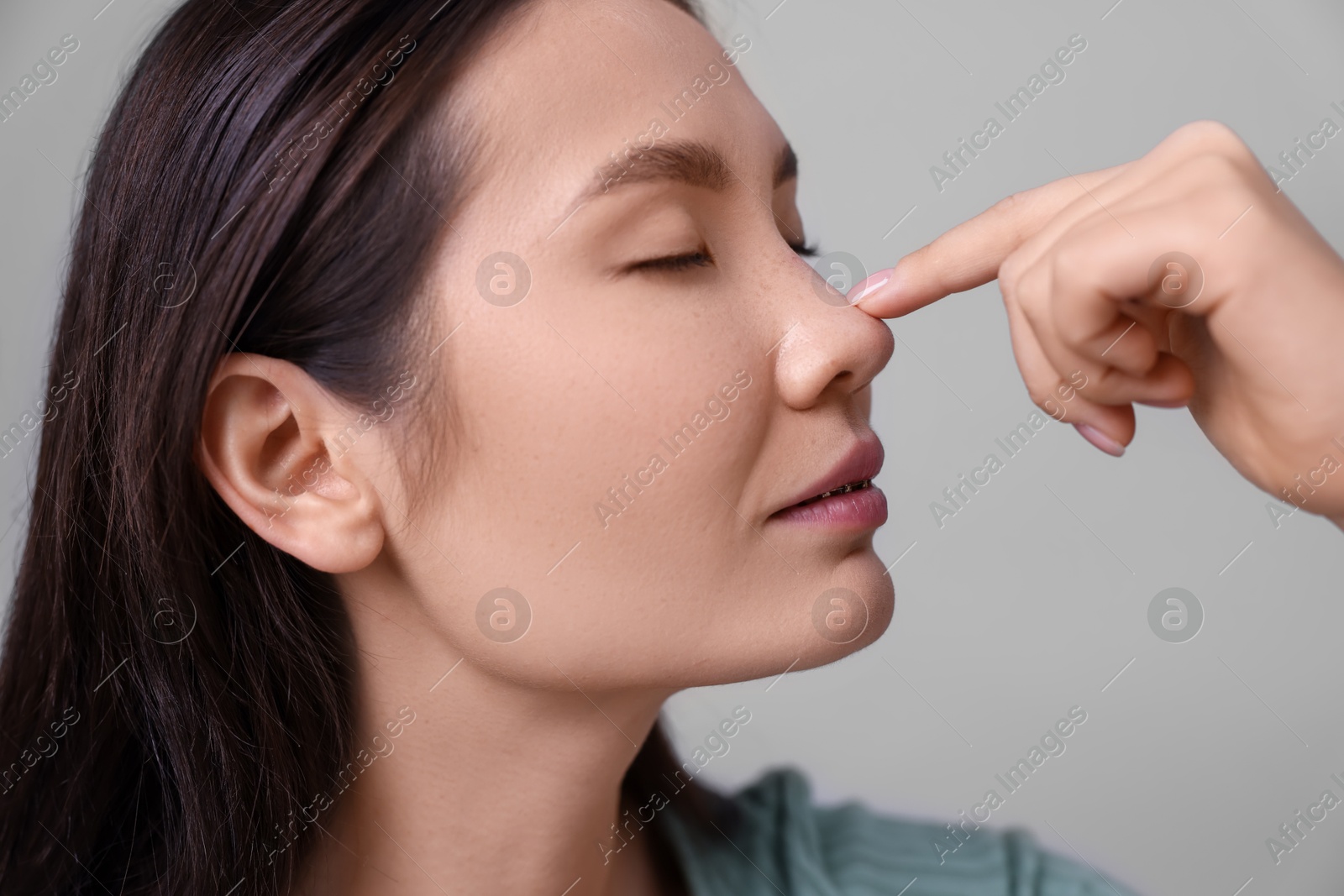 Photo of Woman touching her nose on light grey background, closeup