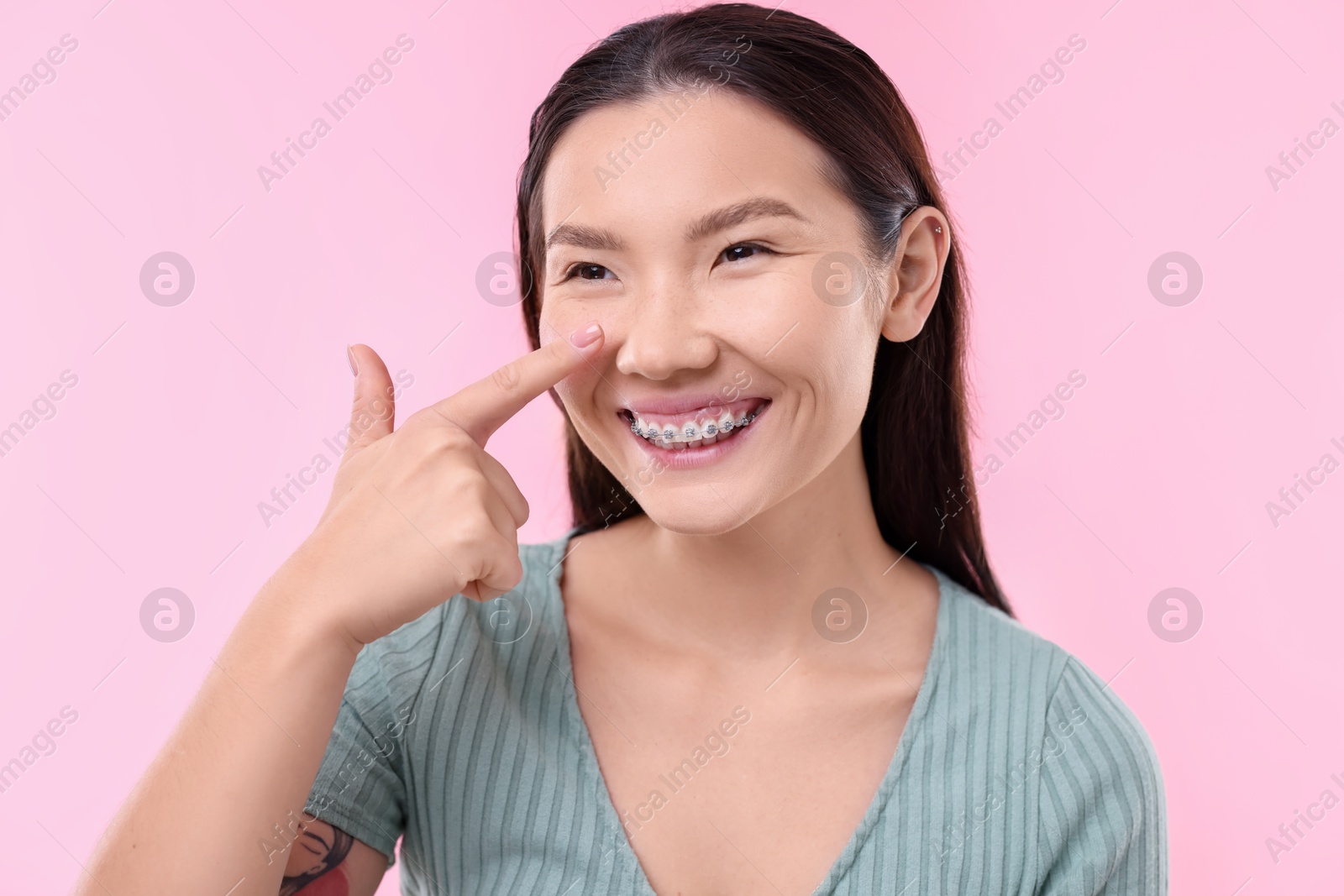 Photo of Woman touching her nose on pink background