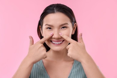 Photo of Woman touching her nose on pink background