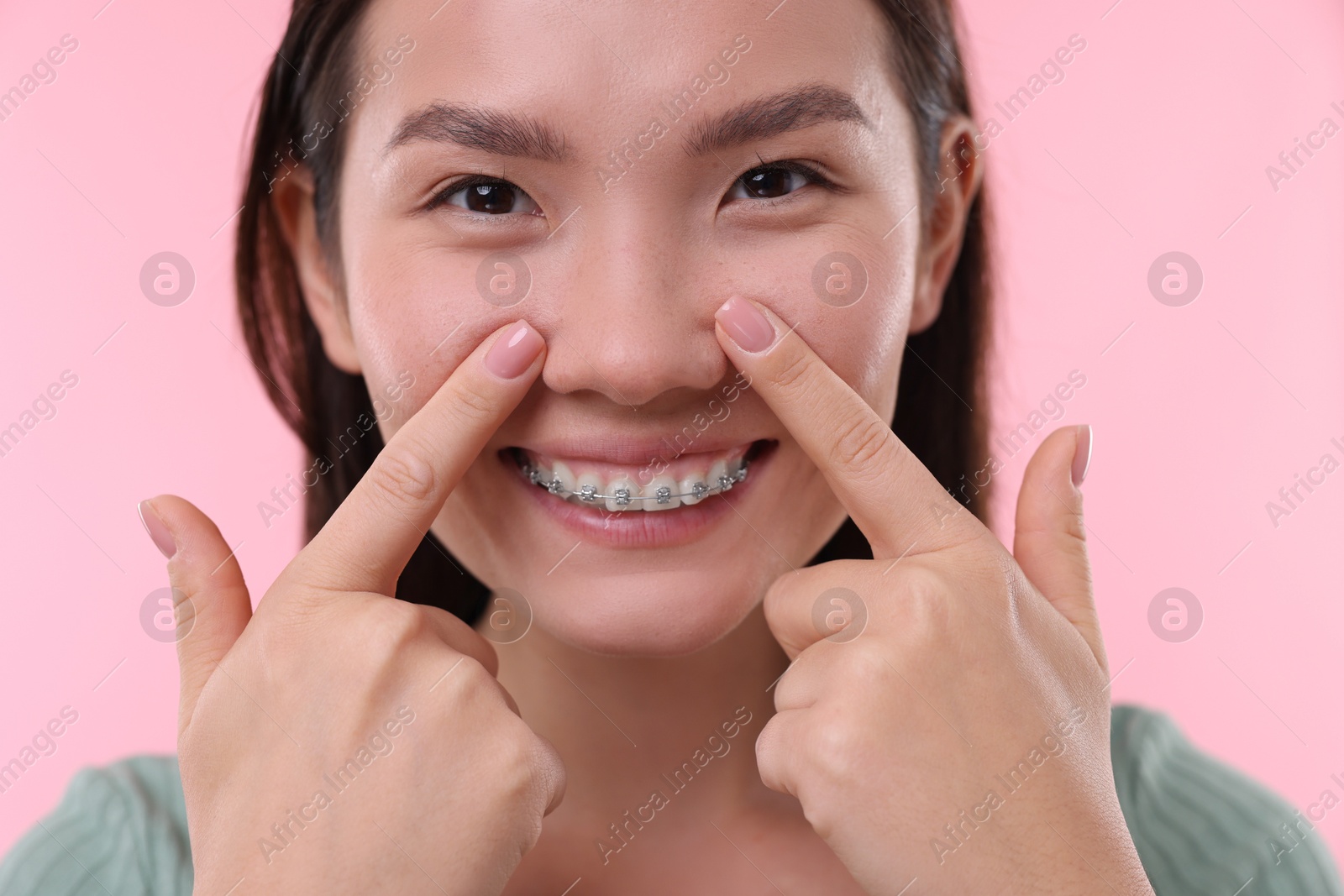 Photo of Woman touching her nose on pink background, closeup