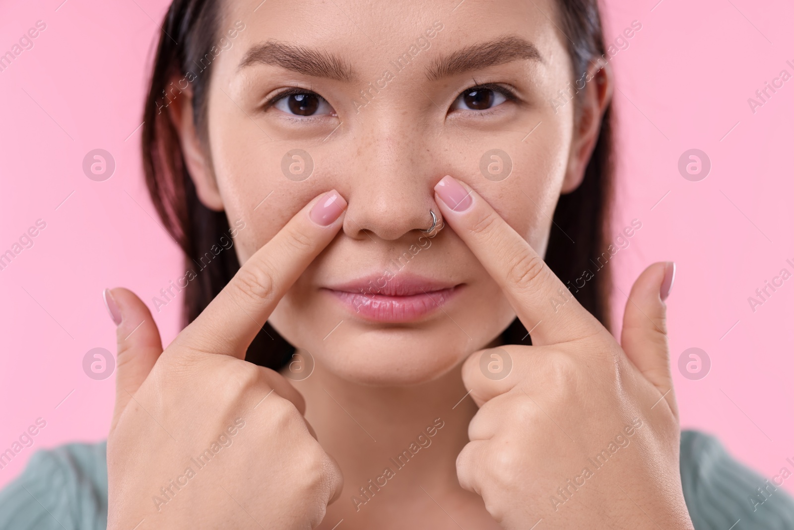 Photo of Woman touching her nose on pink background, closeup