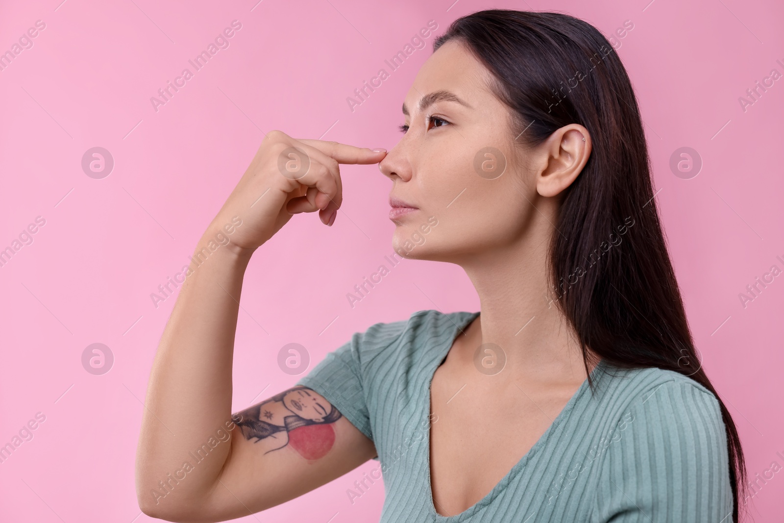 Photo of Woman touching her nose on pink background