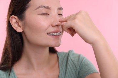 Photo of Woman touching her nose on pink background, closeup