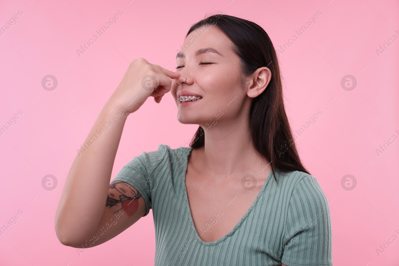 Photo of Woman touching her nose on pink background