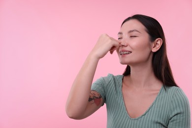 Photo of Woman touching her nose on pink background. Space for text