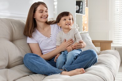 Photo of Happy mother with her cute little son on sofa at home